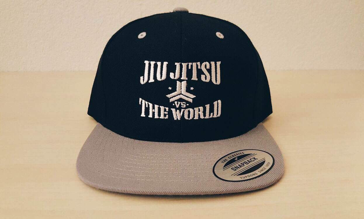 OGA Open Guard Apparel Jiu Jitsu vs The World Snapback hat. Grey black hat with white embroidery. Jiu Jitsu vs the world series from Open guard apparel.